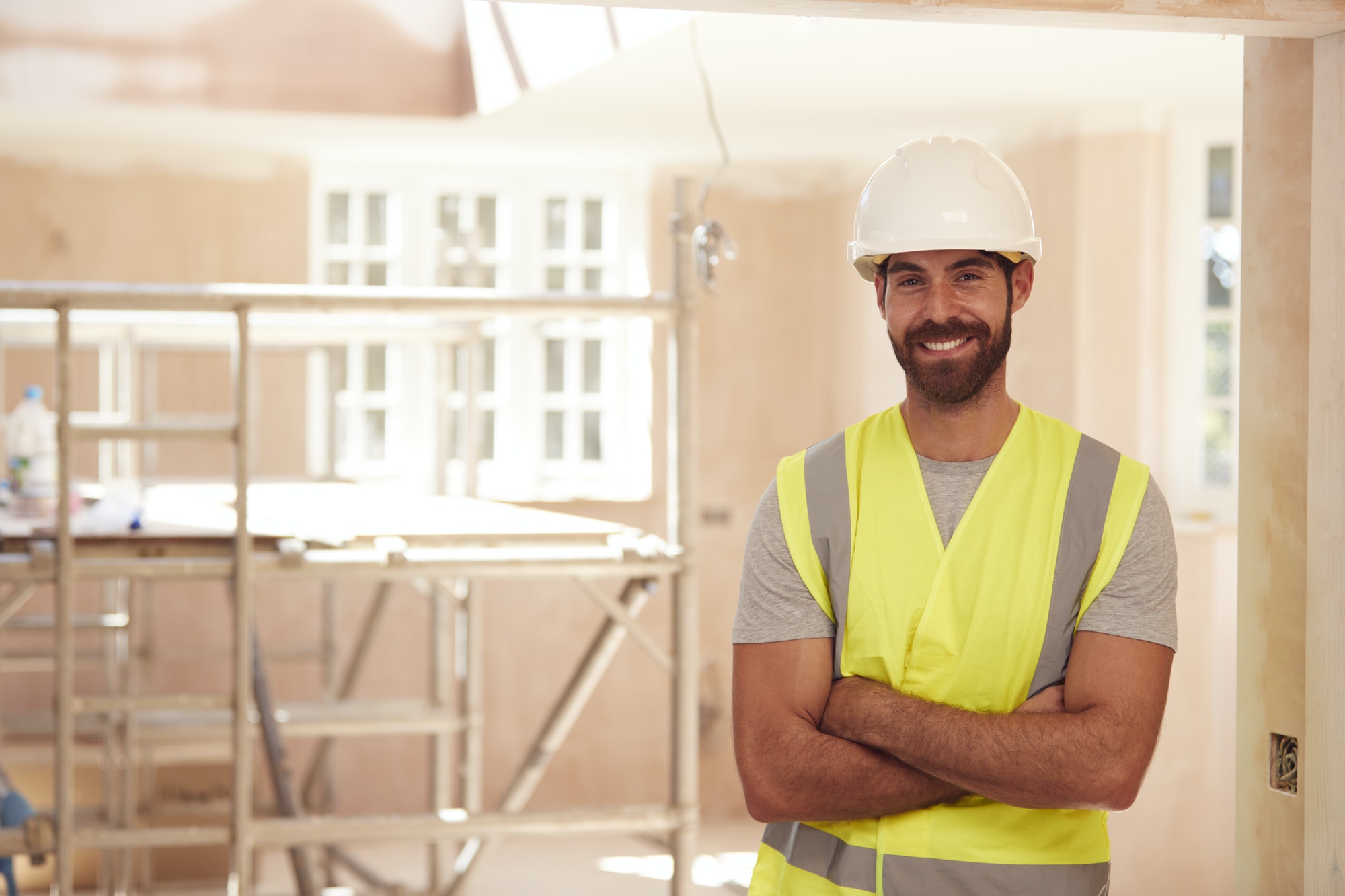 Portrait Of Smiling Male Builder Wearing Hard Hat Working In New Build Property